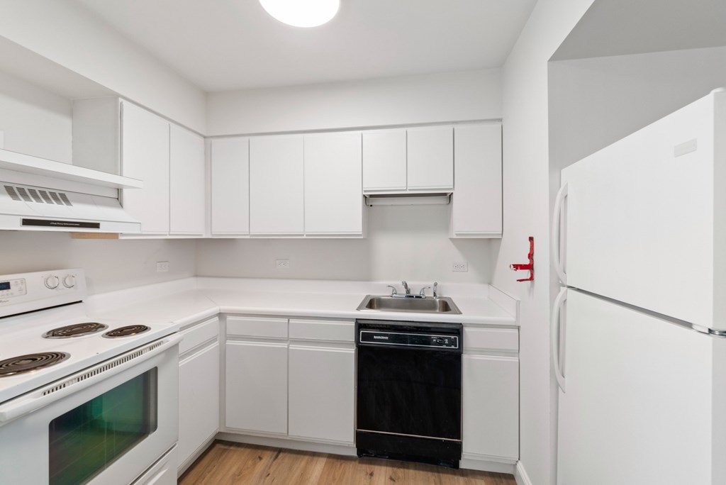 A white kitchen with a stove, oven, dishwasher, and refrigerator.