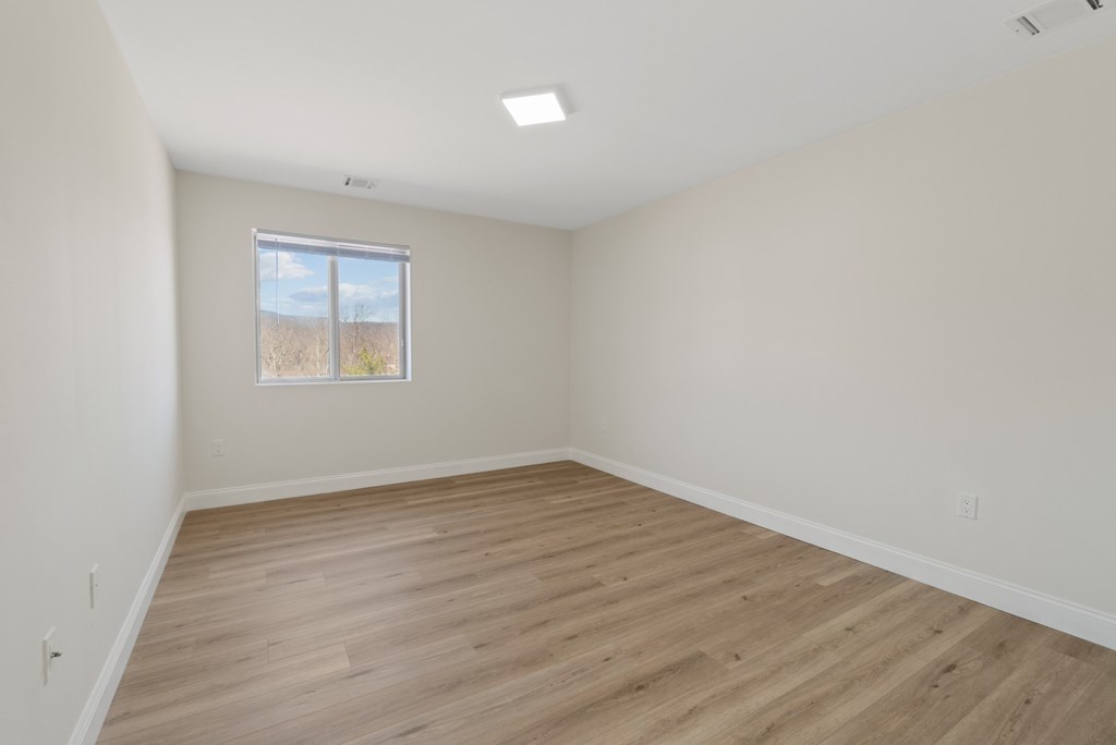 Empty room with wooden flooring and a window.