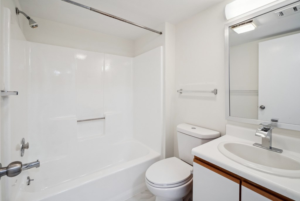 A white bathroom with a toilet, sink, and bathtub.