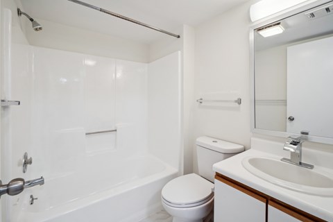 A white bathroom with a toilet, sink, and bathtub.