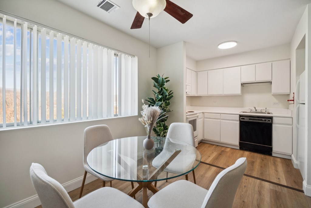 A modern dining room with a glass table and white chairs.
