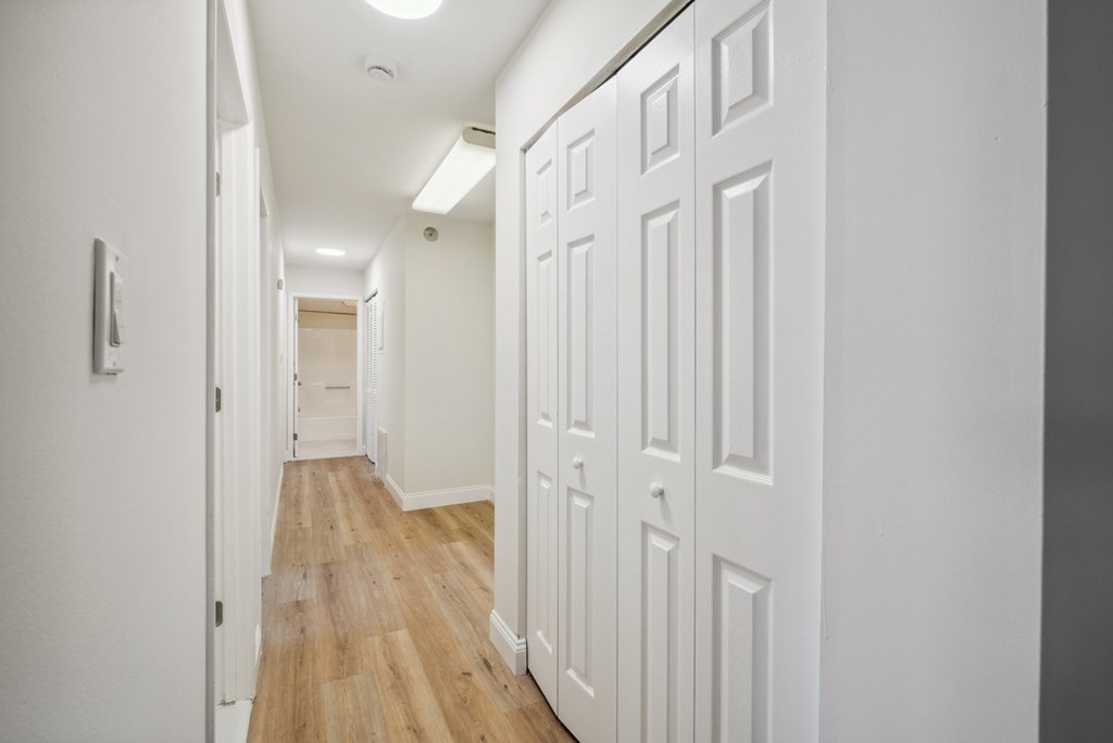 A long hallway with white doors on the right side.