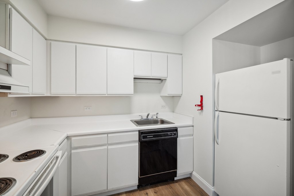 A white kitchen with a black oven and a white fridge.