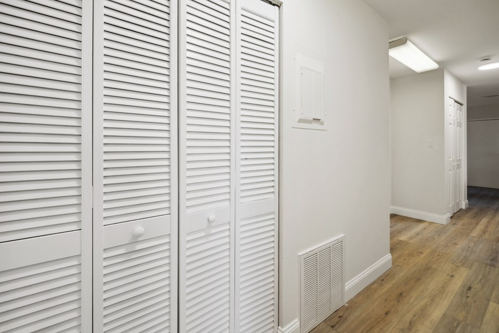 Closed white doors with wood floors and a white wall.