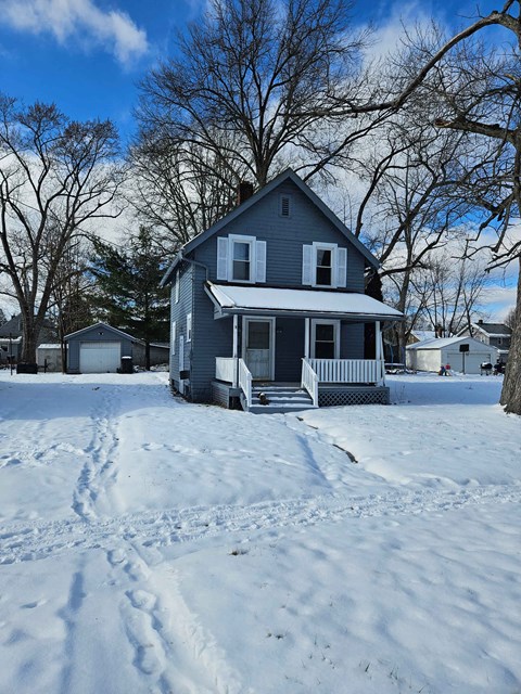 A house with a porch and a snow-covered ground.