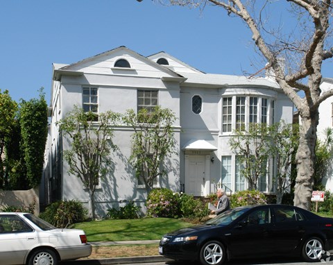 A large white house with a black car parked in front.