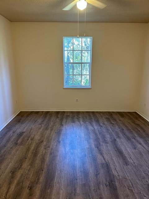 A room with a window and wooden flooring.