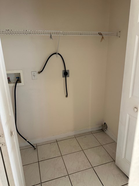 A white bathroom with a white door and a white tiled floor.