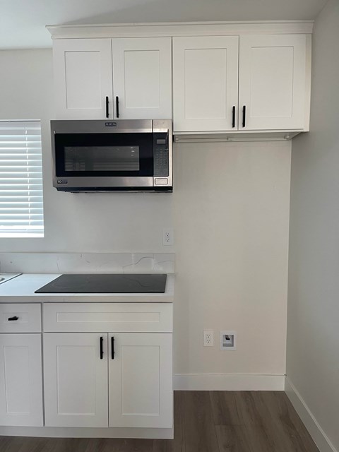 A kitchen with white cabinets and a microwave above the stove.