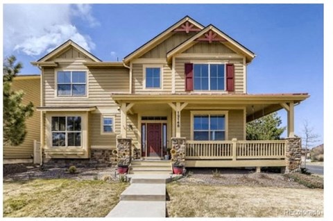 A two-story house with a red door and a balcony.