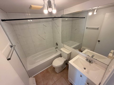 A white bathroom with a toilet, sink, and bathtub.