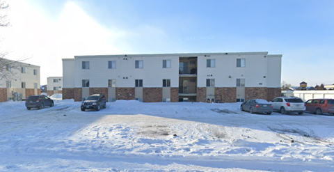 A white building with a parking lot in front of it.