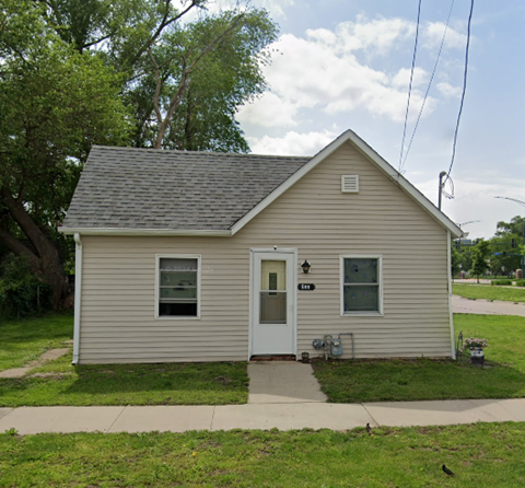 A small house with a grey roof and a white door.