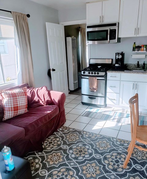 A kitchen with a red couch and a patterned rug.