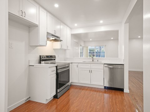 A kitchen with white cabinets and a wooden floor.