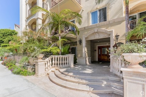 A building with a balcony and a doorway surrounded by plants.