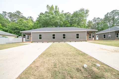 A large building with a grey roof and a long driveway in front.