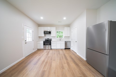 A kitchen with a refrigerator on the right side.
