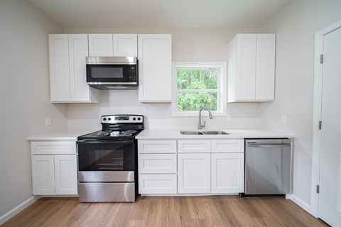 A kitchen with white cabinets and a window.