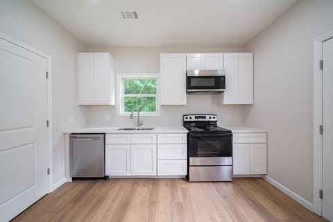 A kitchen with white cabinets and a window.