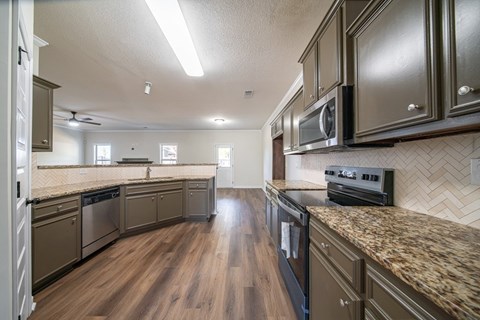 A kitchen with dark wood cabinets and a granite counter.