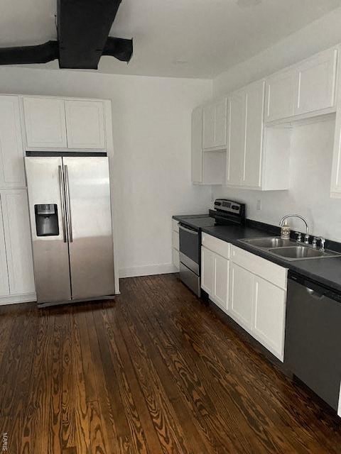 A kitchen with a stainless steel refrigerator and black countertops.