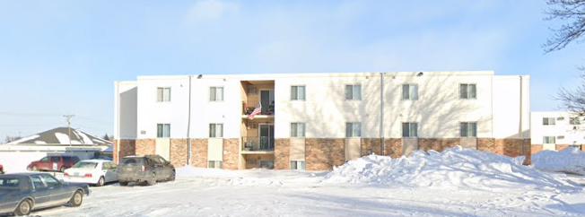 A large white building with a red door and windows is surrounded by snow.