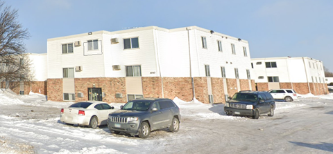 A white building with a parking lot in front of it.