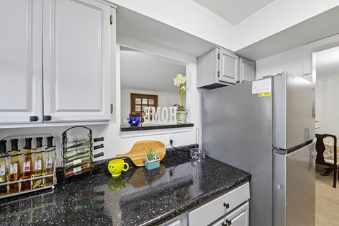 A kitchen with a black counter top and white cabinets.
