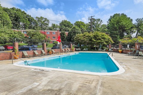 A large outdoor swimming pool surrounded by a fence and trees.
