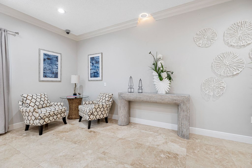A living room with a sofa, armchair, and a table with a vase of flowers.