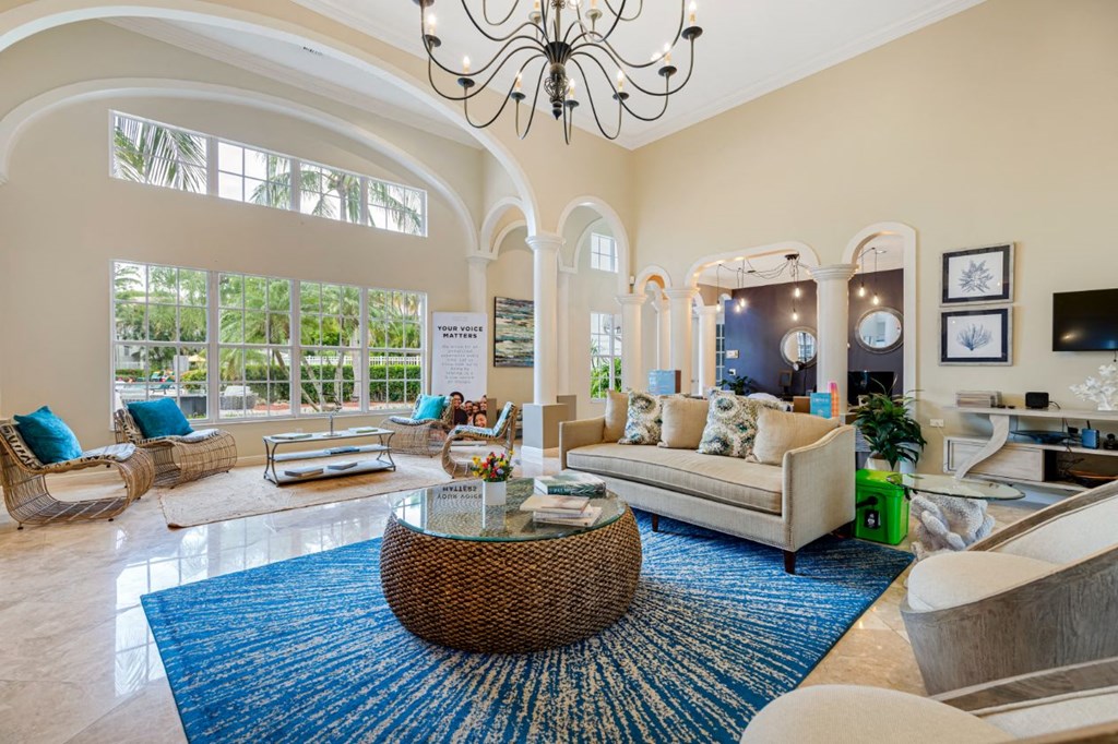 A living room with a wicker coffee table and a couch with blue pillows.