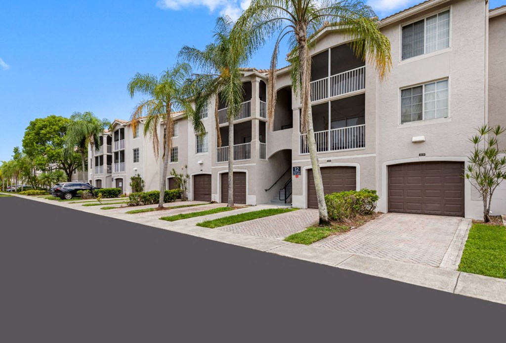A row of modern apartment buildings with palm trees in front.