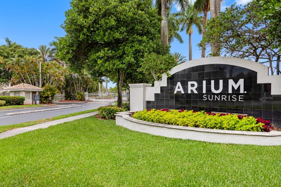 A sign that says "ARIUM SUNRISE" is in front of a grassy area.