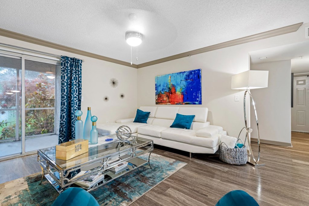 A living room with a white couch and a large painting on the wall.