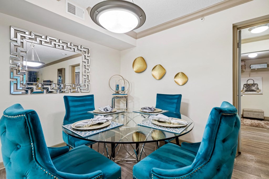 A dining room with a glass table and blue chairs.