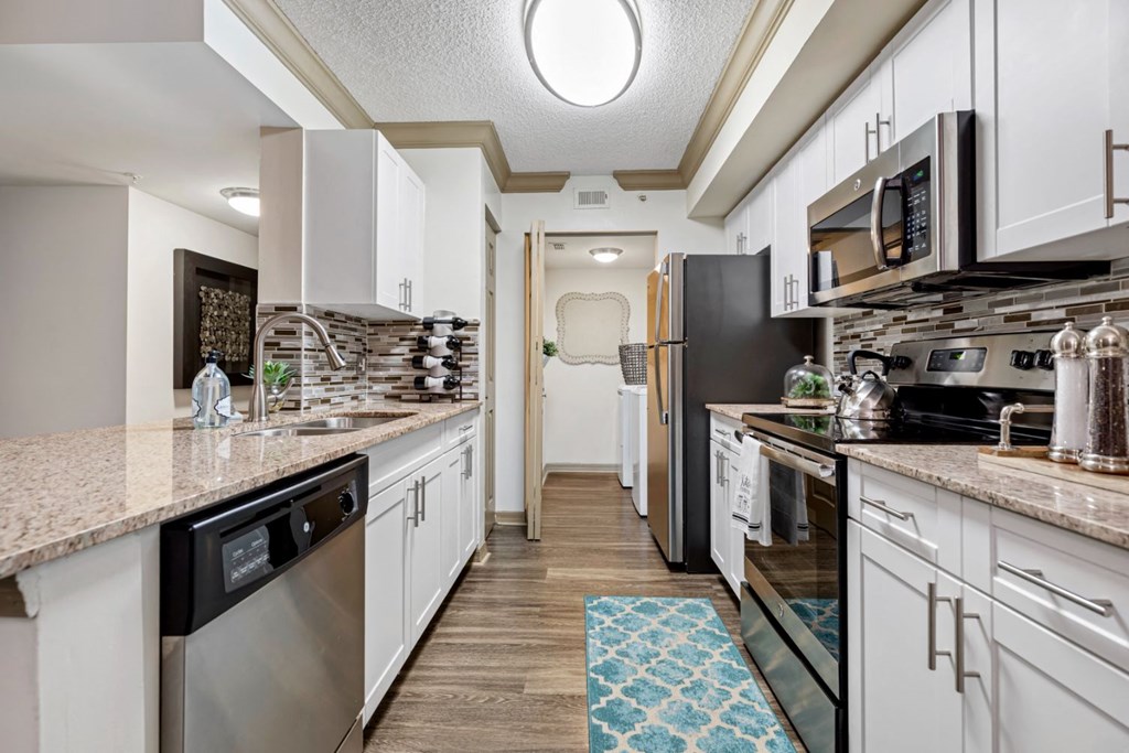 A kitchen with white cabinets and a black refrigerator.