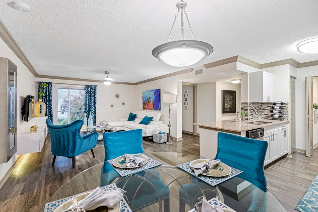 A modern dining room with a glass table and blue chairs.