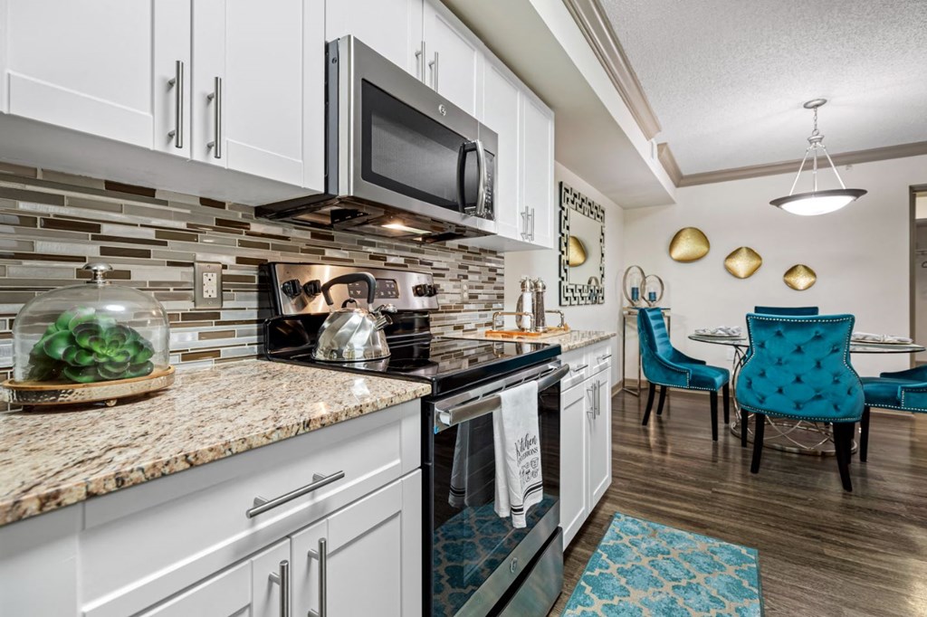 A kitchen with a granite countertop and a blue chair.