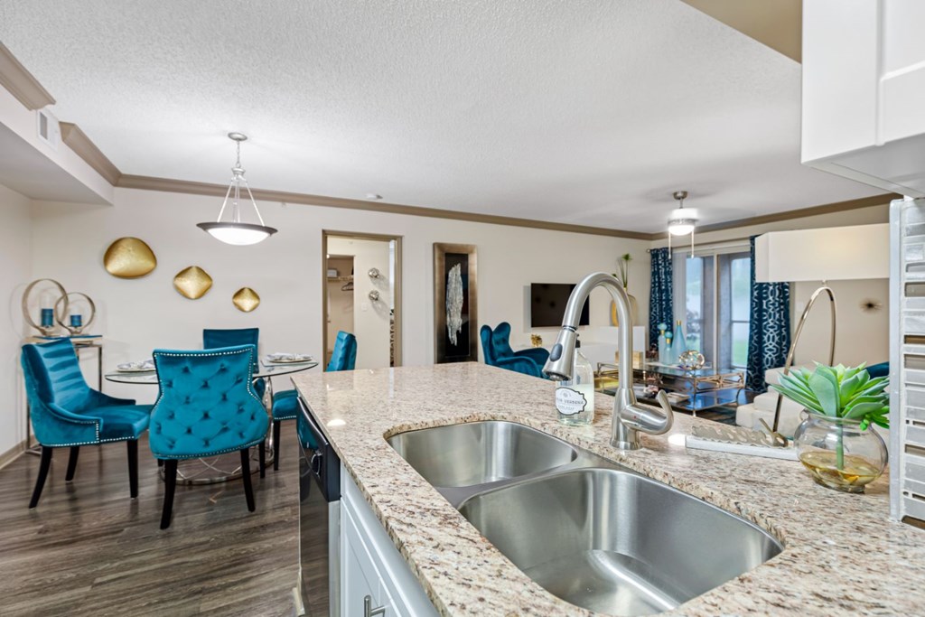A kitchen with a blue chair and a stainless steel sink.