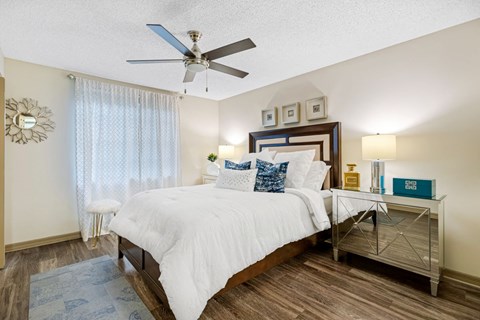 A bedroom with a bed, nightstand, and a ceiling fan.