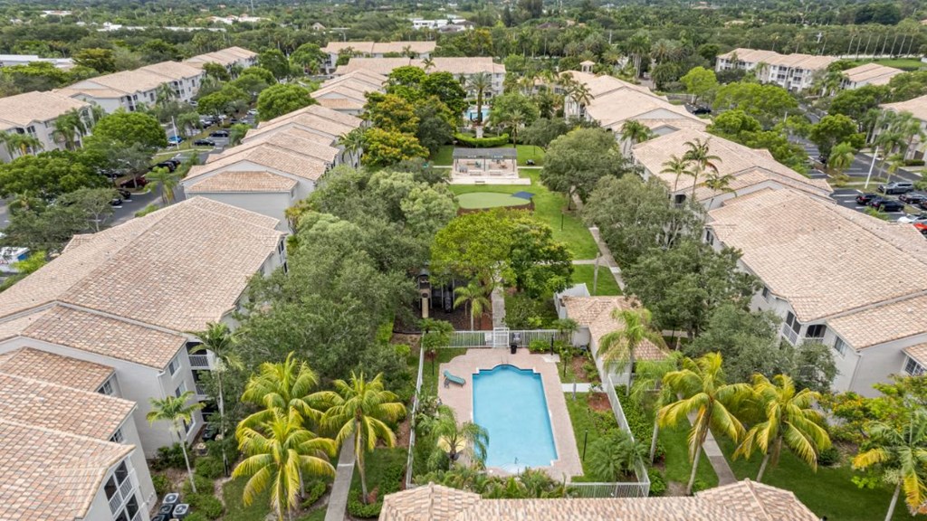 A bird's eye view of a residential area with a swimming pool surrounded by palm trees.
