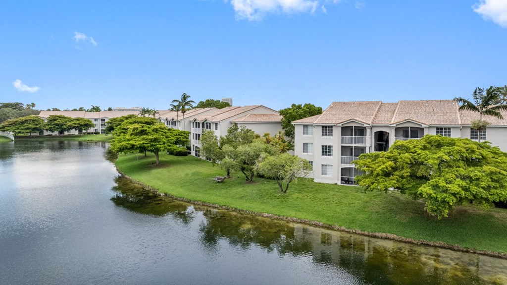 A serene lakeside view with a building and lush greenery.