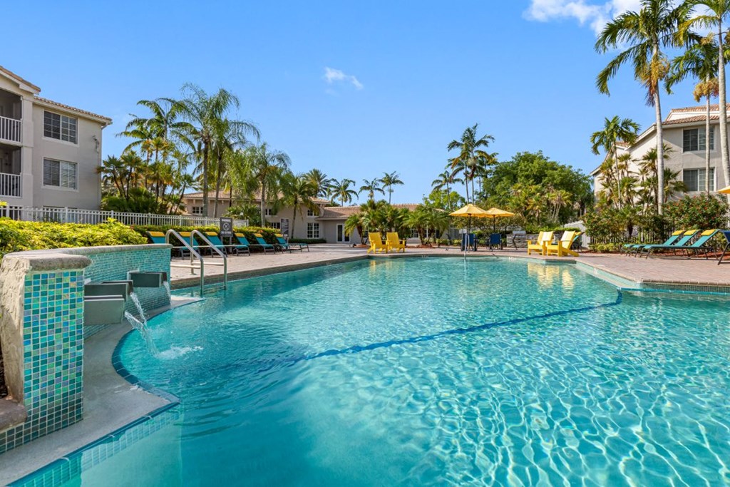 A swimming pool surrounded by palm trees and buildings.