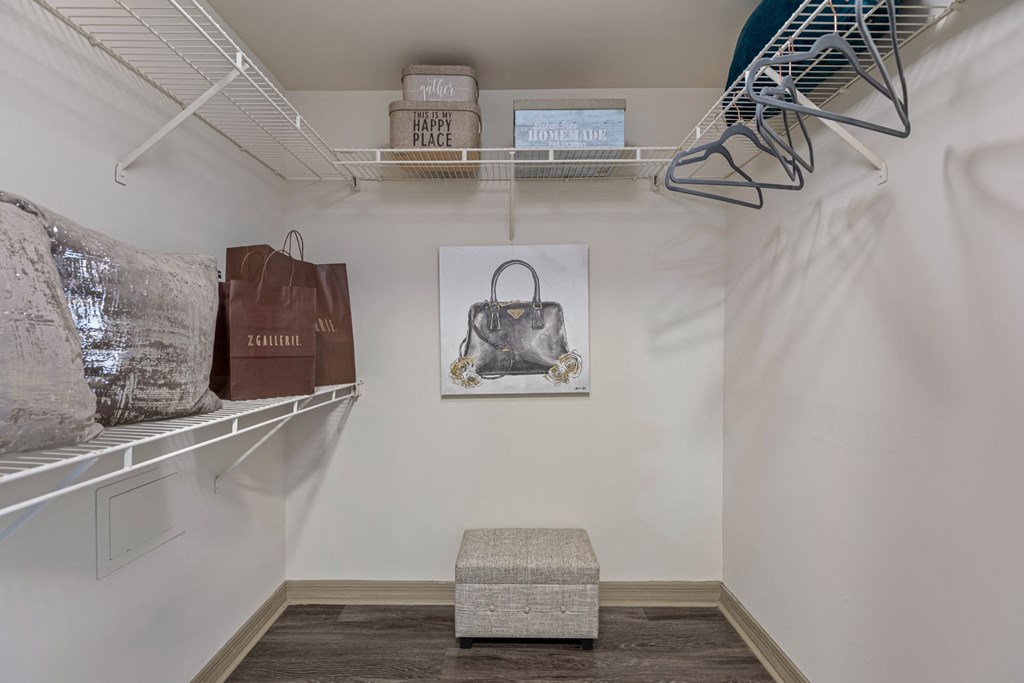 A room with a shelf, a bench, and a picture of a handbag.