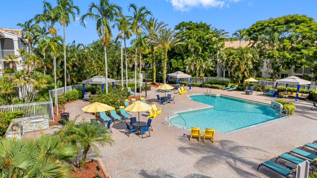 A pool surrounded by palm trees and umbrellas.
