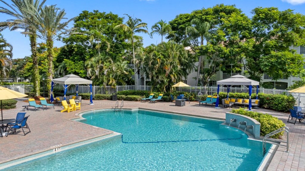 A large swimming pool surrounded by palm trees and lounge chairs.