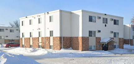 A white building with a red car parked in front of it.