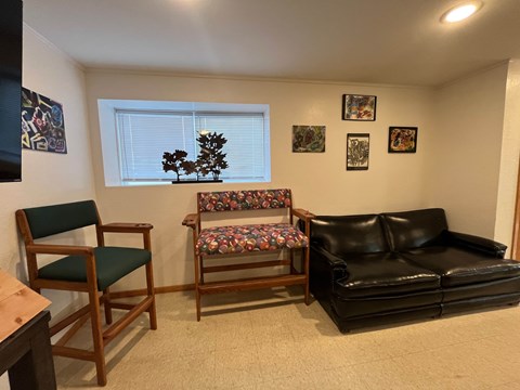 A living room with a black couch, a wooden chair, and a wooden bench.