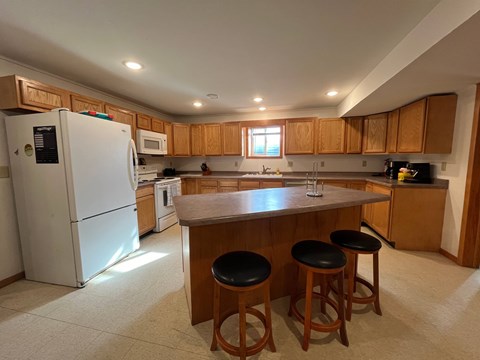 A kitchen with a white refrigerator and wooden cabinets.